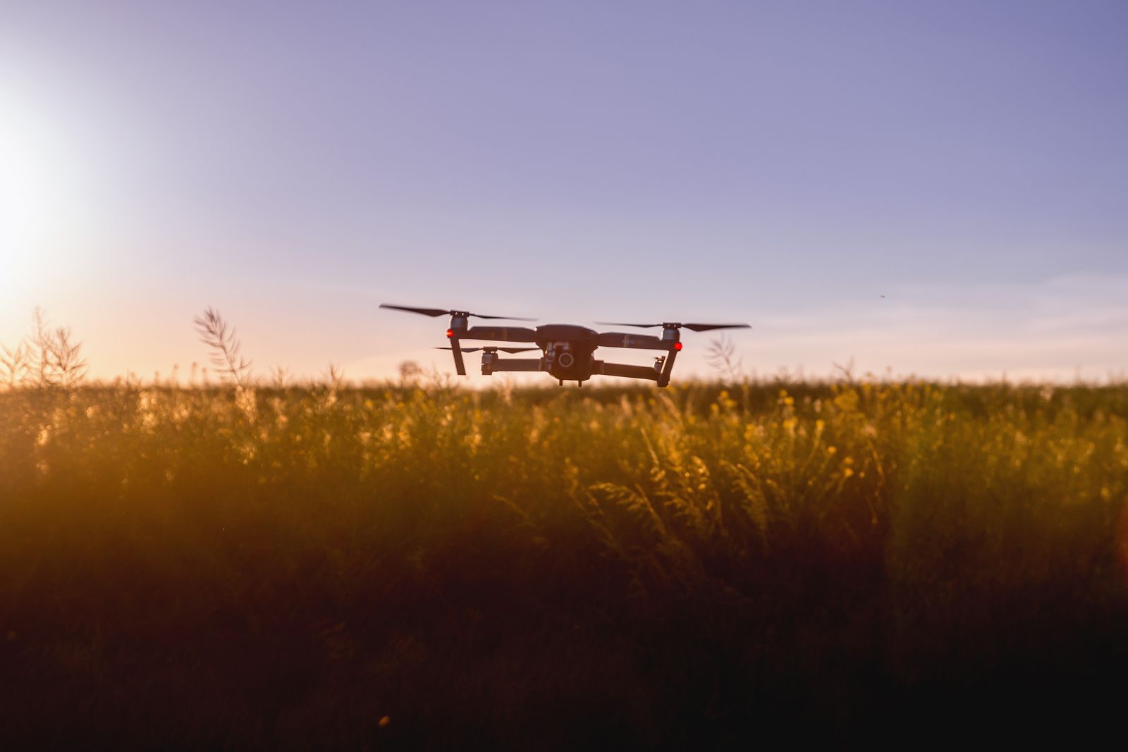 A survey drone hovering over crops at dusk